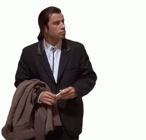 A Man In A Suit With A Bolo Tie Around His Neck Is Holding A Jacket GIF