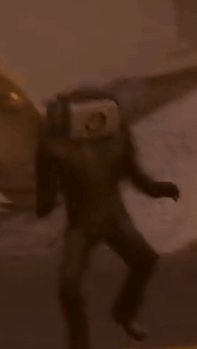 A Man In A Suit With A Camera On His Head Is Walking Down The Street . GIF