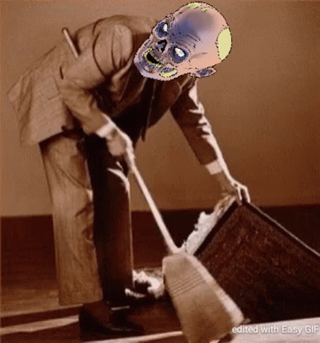 A Man In A Suit With A Zombie Face On His Head Is Cleaning A Coffin GIF
