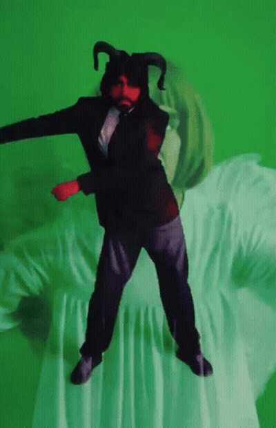 A Man In A Suit With Horns Is Dancing On A Green Background GIF