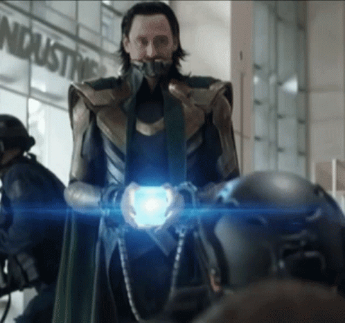 A Man In A Superhero Costume Holds A Blue Object In Front Of A Sign That Says Industry GIF