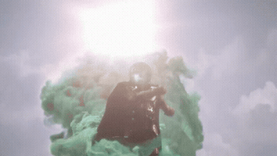 A Man In A Superhero Costume Is Flying Through A Cloud Of Green Smoke GIF