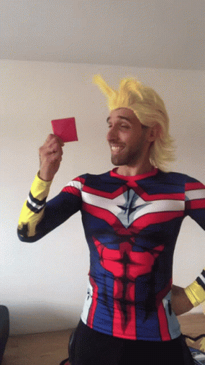 A Man In A Superhero Costume Is Holding Up A Red Card GIF