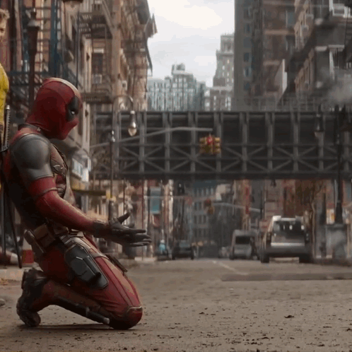 A Man In A Superhero Costume Is Kneeling Down On A City Street GIF