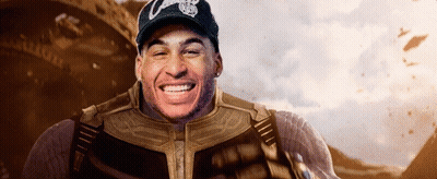 A Man In A Superhero Costume Is Smiling While Wearing A Hat With The Letter C On It . GIF