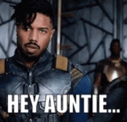 A Man In A Superhero Costume Is Standing In A Room With The Words `` Hey Auntie '' Written On It . GIF
