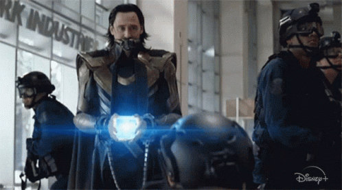 A Man In A Superhero Costume Is Standing In Front Of A Building With The Word Industries On It . GIF