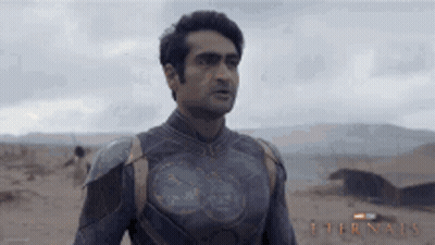 A Man In A Superhero Costume Is Standing In The Desert Looking At Something . GIF