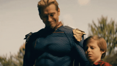 A Man In A Superhero Costume Is Standing Next To A Little Boy GIF