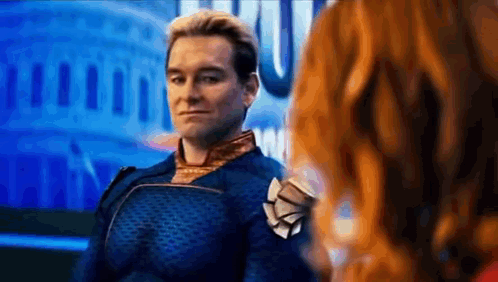 A Man In A Superhero Costume Is Standing Next To A Woman In Front Of A Building . GIF
