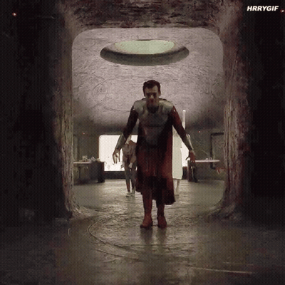 A Man In A Superhero Costume Is Walking Through A Tunnel In A Cave . GIF