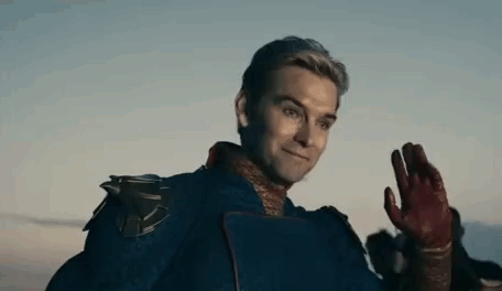 A Man In A Superhero Costume Is Waving His Hand At The Camera . GIF