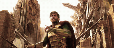 A Man In A Superhero Costume Stands In Front Of A Brick Building GIF