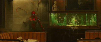 A Man In A Superhero Costume Stands In Front Of A Fish Tank GIF