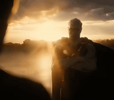 A Man In A Superhero Costume Stands In Front Of The Sun GIF