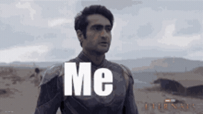 A Man In A Superhero Suit Is Standing In The Desert With The Words `` Me '' Written On His Chest . GIF