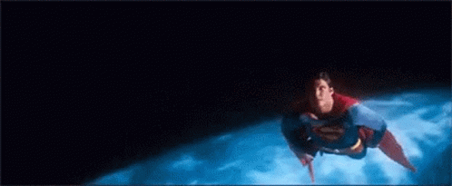A Man In A Superman Costume Is Flying Through The Air Over A Planet . GIF