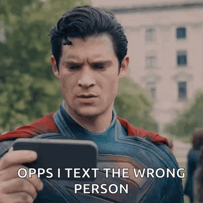 A Man In A Superman Costume Is Holding A Cell Phone And Says " Opps I Text The Wrong Person " . GIF