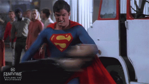 A Man In A Superman Costume Is Standing In Front Of A White Truck .. GIF