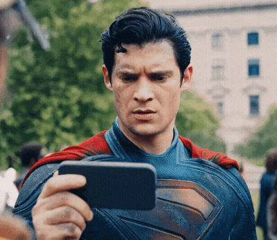 A Man In A Superman Costume Is Taking A Picture Of Himself With A Cell Phone GIF