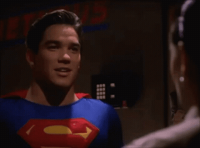 A Man In A Superman Costume Is Talking To Another Man In A Room . GIF
