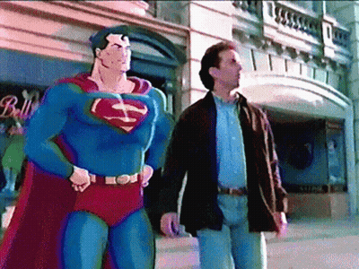 A Man In A Superman Costume Stands Next To A Man In A Brown Jacket GIF