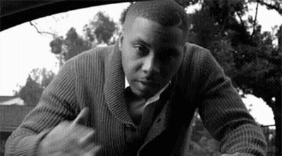 A Man In A Sweater And Tie Is Standing In A Car . GIF