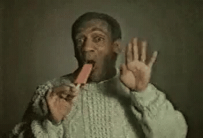 A Man In A Sweater Is Eating An Ice Cream Cone And Making A Funny Face . GIF