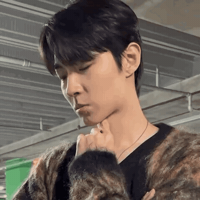 A Man In A Sweater Is Holding His Hand To His Chin . GIF