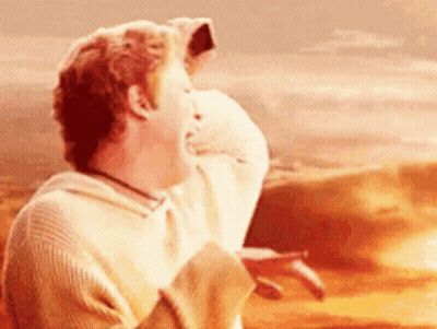 A Man In A Sweater Is Laughing In Front Of A Desert . GIF