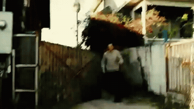 A Man In A Sweater Is Running Down A Sidewalk GIF
