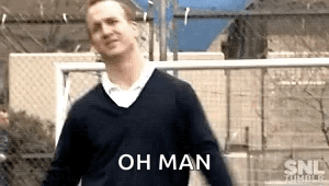 A Man In A Sweater Is Standing In Front Of A Fence With The Words Oh Man Written On It . GIF