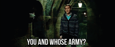 A Man In A Sweater Says " You And Whose Army " In A Dark Hallway GIF