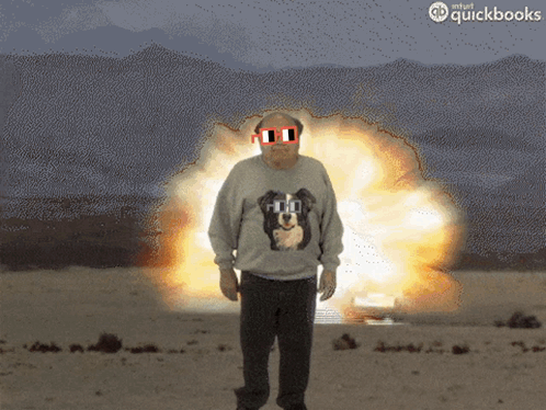 A Man In A Sweater With A Dog On It Stands In Front Of An Explosion GIF