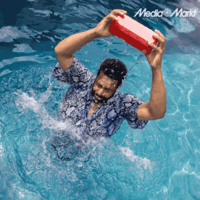 A Man In A Swimming Pool Is Holding A Red Box Over His Head With The Media Markt Logo In The Corner GIF