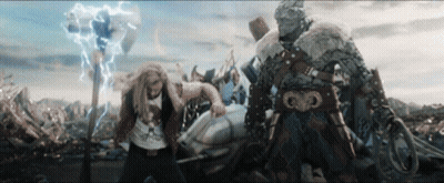 A Man In A T-Shirt That Says ' Thor ' On It Stands Next To Another Man GIF