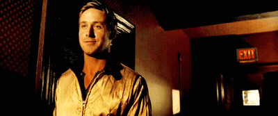 A Man In A Tan Jacket Stands In Front Of An Exit Sign GIF