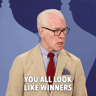 A Man In A Tan Suit And Red Tie Says You All Look Like Winners GIF