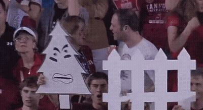 A Man In A Tango Shirt Holds Up A Sign GIF