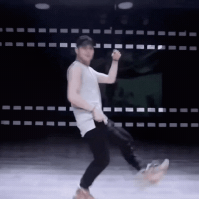 A Man In A Tank Top And Black Pants Is Dancing On A Stage . GIF