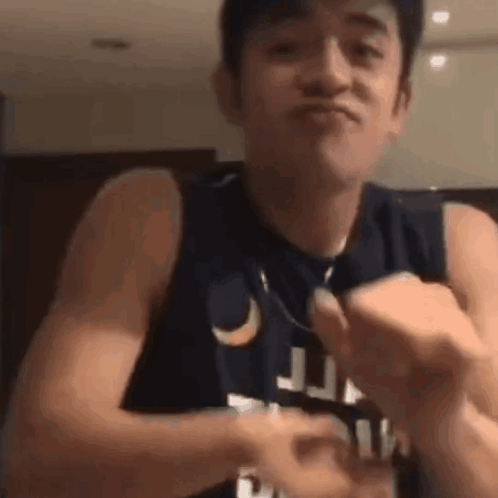 A Man In A Tank Top Is Making A Funny Face While Holding Something In His Hands . GIF