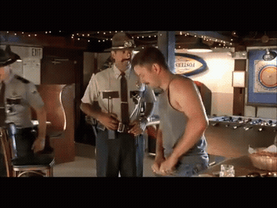 A Man In A Tank Top Is Standing In Front Of A Police Officer In A Bar GIF