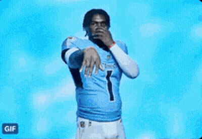 A Man In A Tennessee Titans Jersey Is Dancing In Front Of A Blue Background . GIF