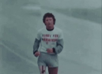 A Man In A Terry Fox Marathon Shirt Is Running On A Road . GIF