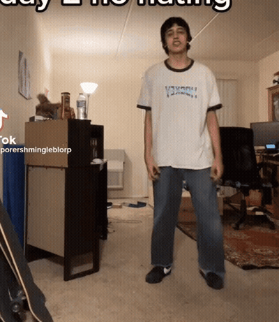 A Man In A Thrasher Shirt Is Standing In A Room GIF