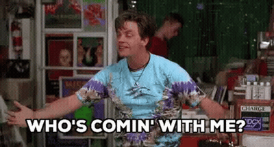 A Man In A Tie Dye Shirt Is Standing In Front Of A Record Store . GIF