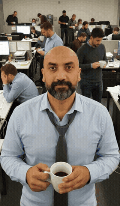 A Man In A Tie Holds A Cup Of Coffee In An Office GIF