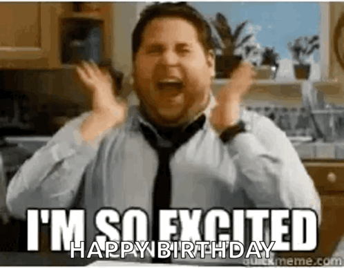 A Man In A Tie Is Celebrating His Birthday In A Kitchen With His Hands In The Air . GIF