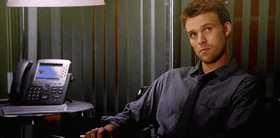 A Man In A Tie Is Sitting In Front Of A Desk With A Telephone . GIF
