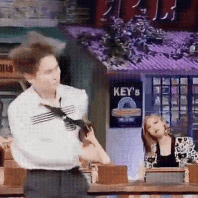 A Man In A Tie Is Standing In Front Of A Sign That Says Key 'S On It . GIF